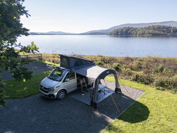 Vango drive-away awning attached to a campervan pitched next to a lake in the British countryside