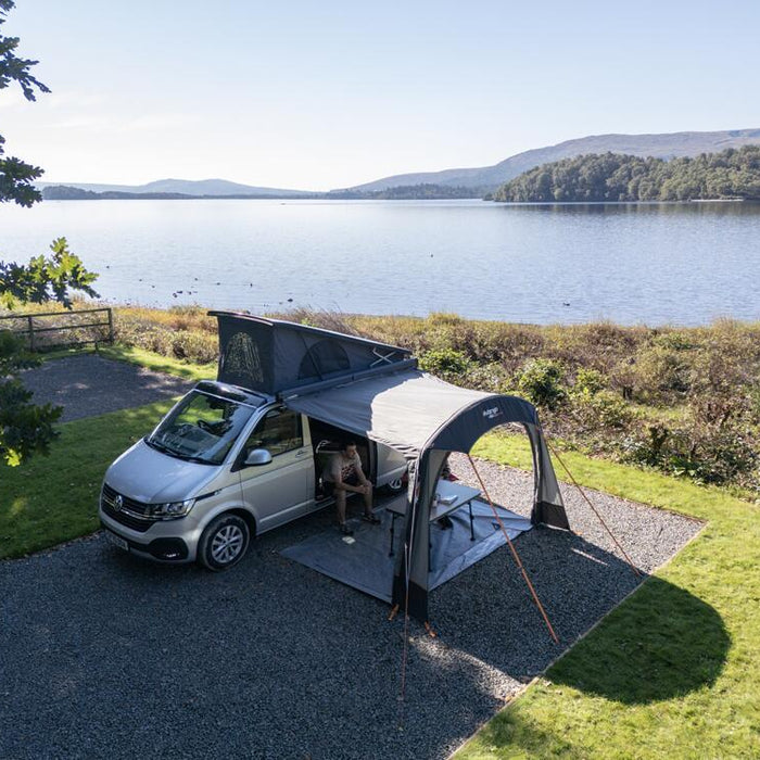 Vango drive-away awning attached to a campervan pitched next to a lake in the British countryside