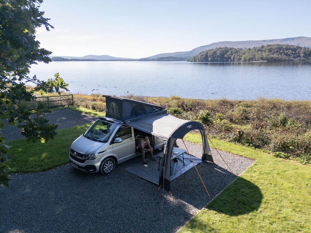 Vango drive-away awning attached to a campervan pitched next to a lake in the British countryside