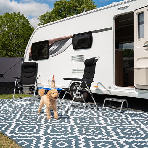 Caravan with camping chairs set up outside on a sunny pitch ready for outdoor relaxation
