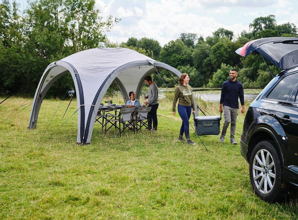 Coleman Event Shelter Air inflatable gazebo with a couple unpacking their car