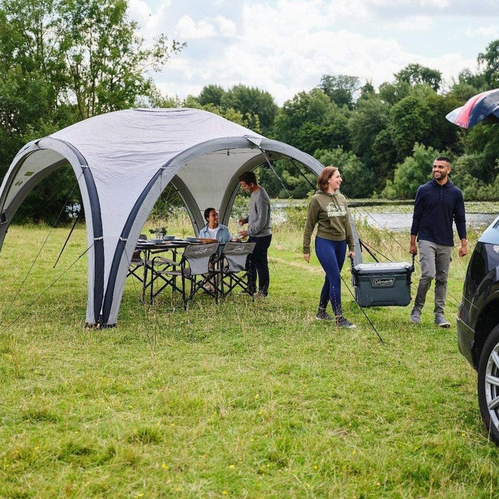 Coleman Event Shelter Air inflatable gazebo with a couple unpacking their car