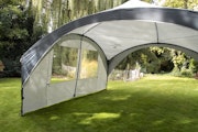 Gazebo with a single side wall panel pitched outdoors on grass in summer sunshine