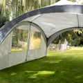 Gazebo with a single side wall panel pitched outdoors on grass in summer sunshine