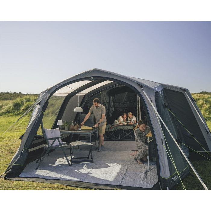 Family camping setup with table, chairs and sleeping area outdoors