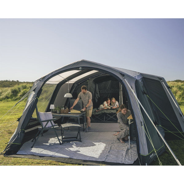 Family camping setup with table, chairs and sleeping area outdoors