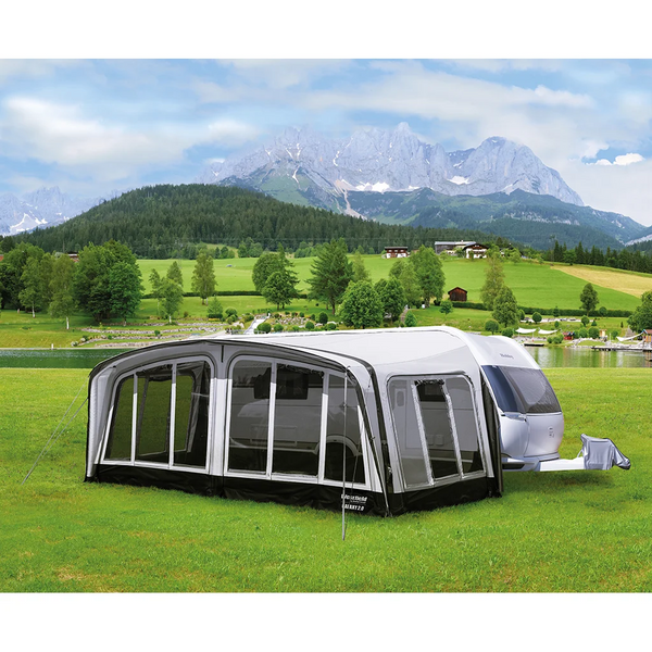 Full caravan awning pitched on a grassy site with mountain range backdrop