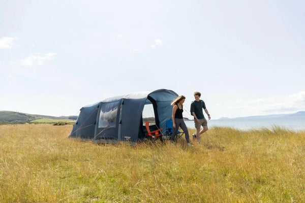Vango 2 person tent pitched in a grassy field with a man admiring the view in sunshine