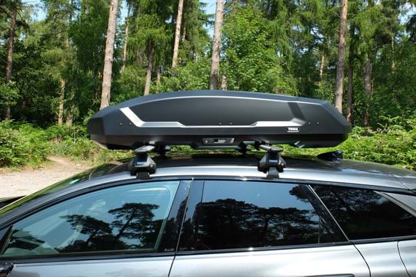 Thule Force 3 roof box mounted on Thule roof bars on a black vehicle parked in a forest