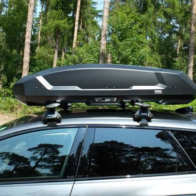 Thule Force 3 roof box mounted on Thule roof bars on a black vehicle parked in a forest